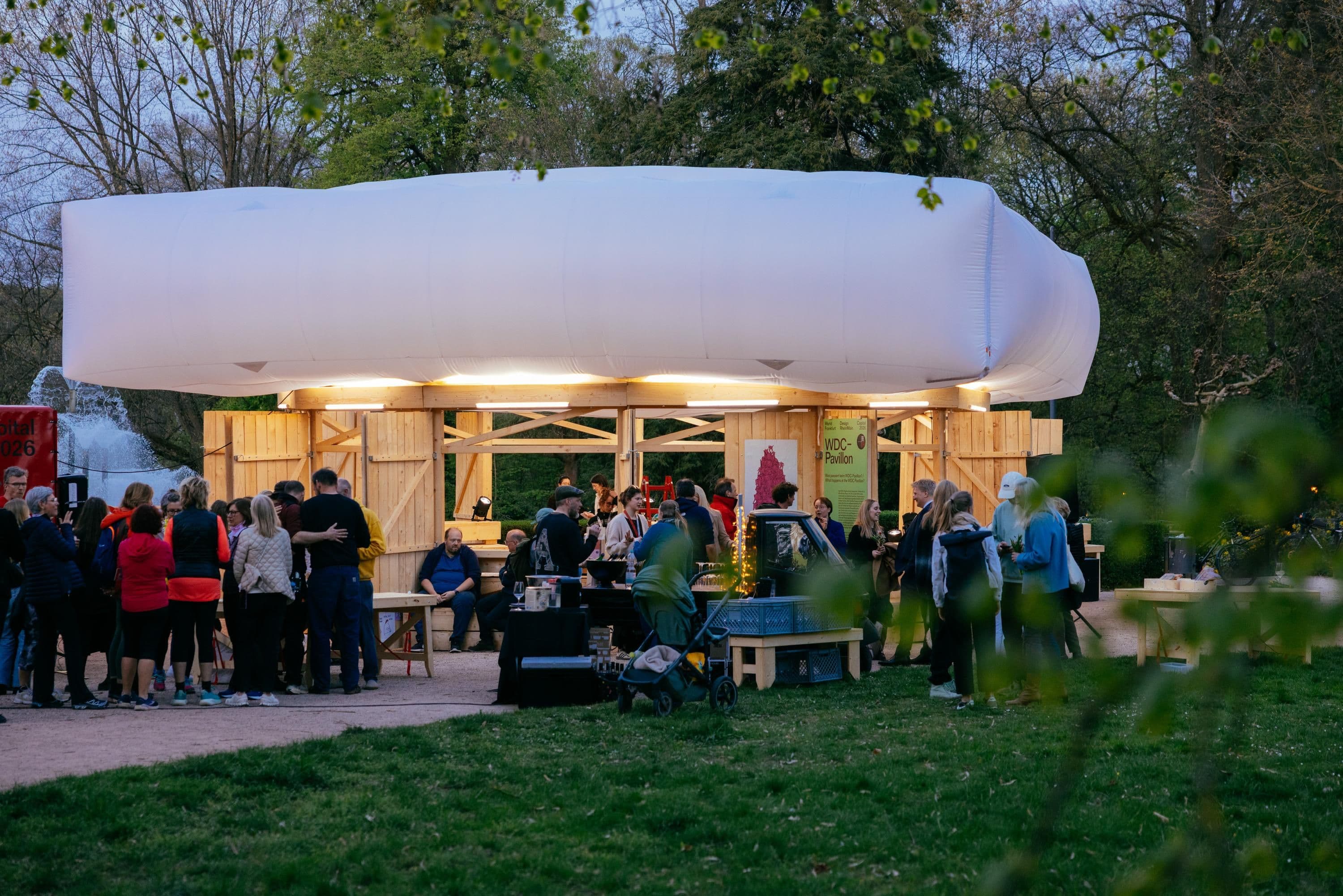 Der WDC-Pavillon aus Holz und einem weißen Dach steht auf einer grünen Wiese.
