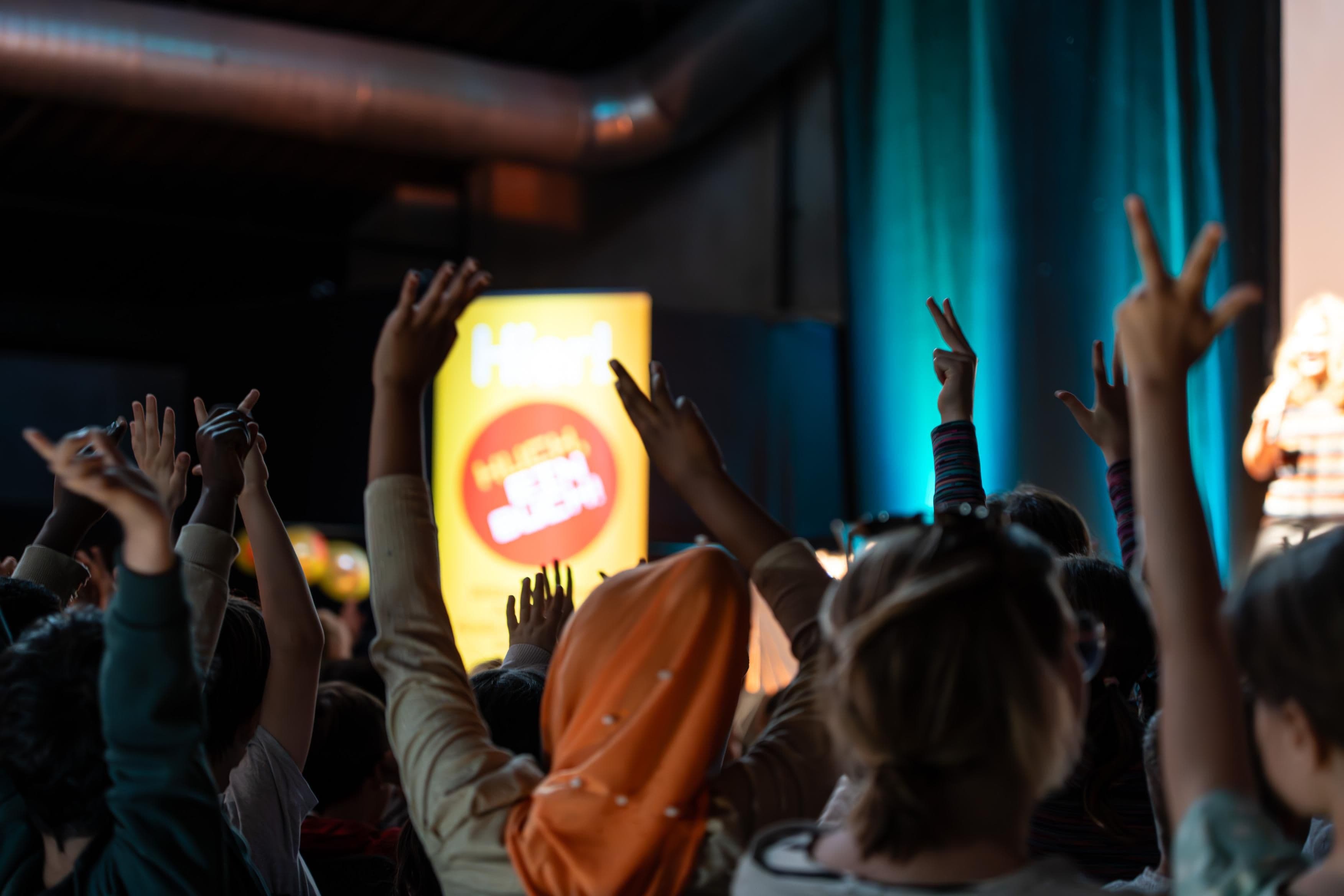 Hände aus dem Publikum zeigen während einer Veranstaltung auf