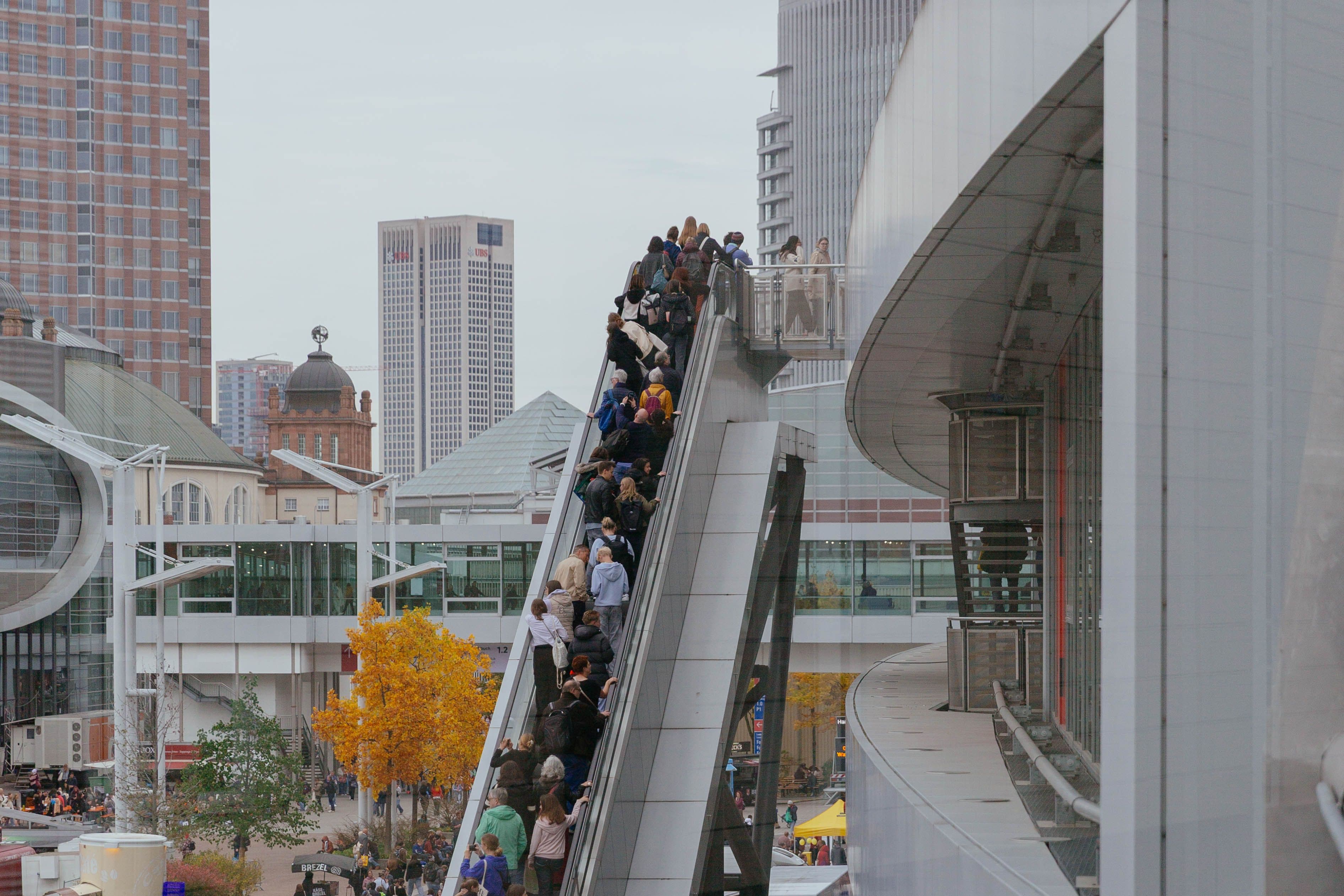 Menschen fahren auf einer außenstehenden Rolltreppe nach oben. 