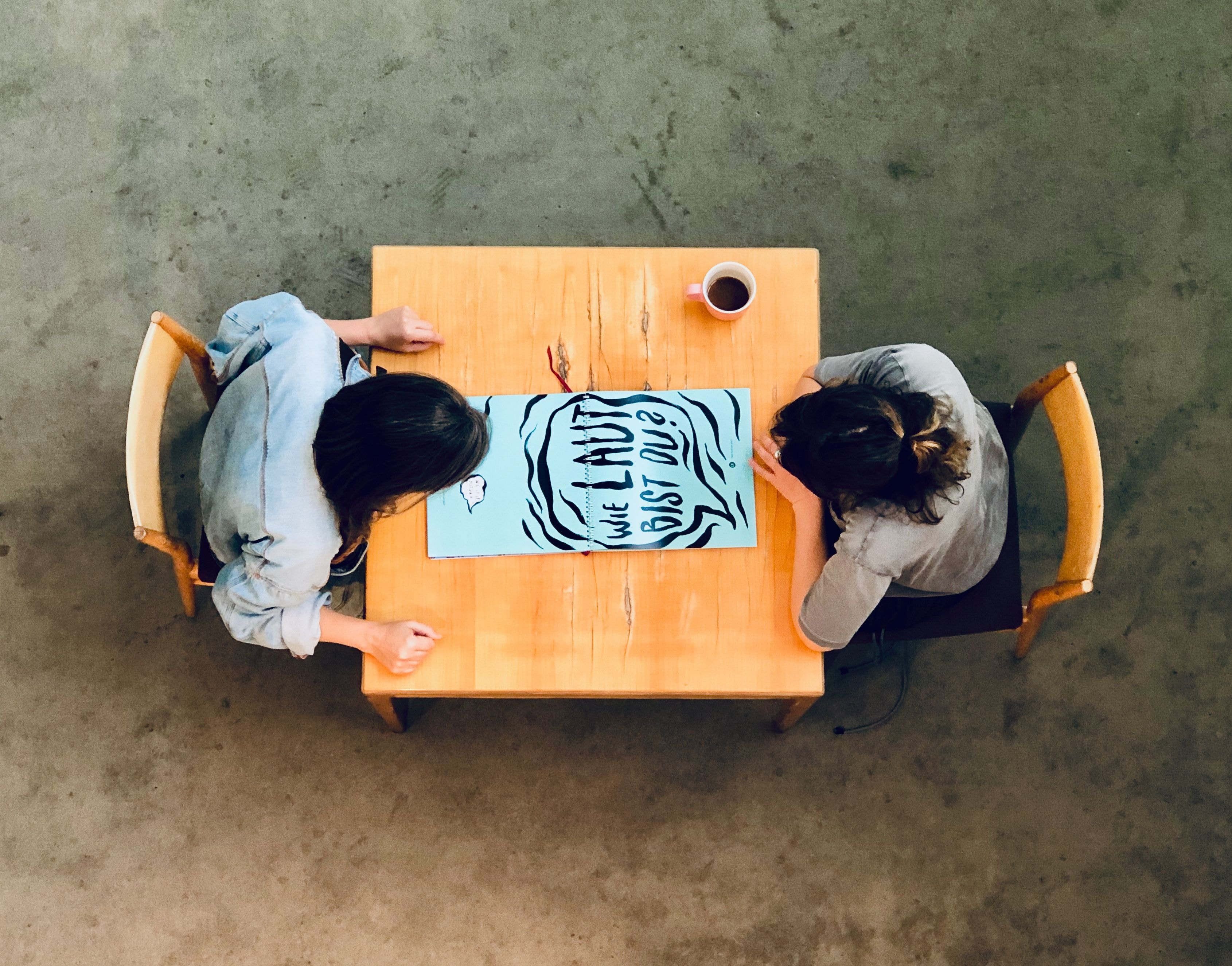 Zwei Personen sitzen an einem Tisch und diskutieren über ein Plakat.