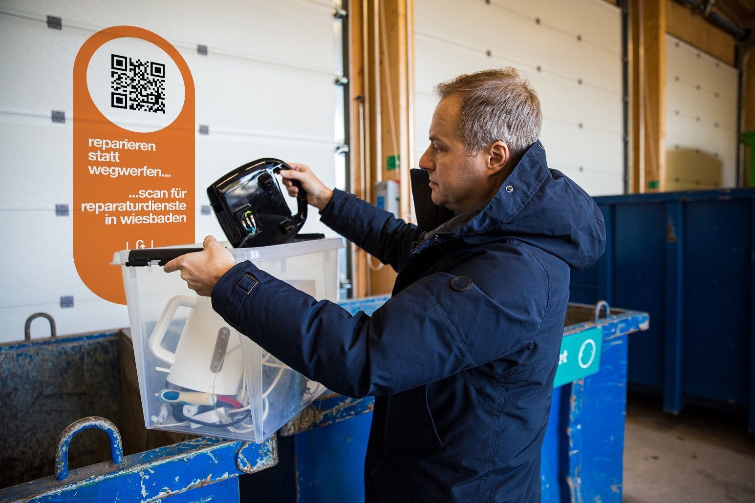 Ein Mann steht an einer Tonne und hält eine Kiste mit Geräten in seinen Händen.