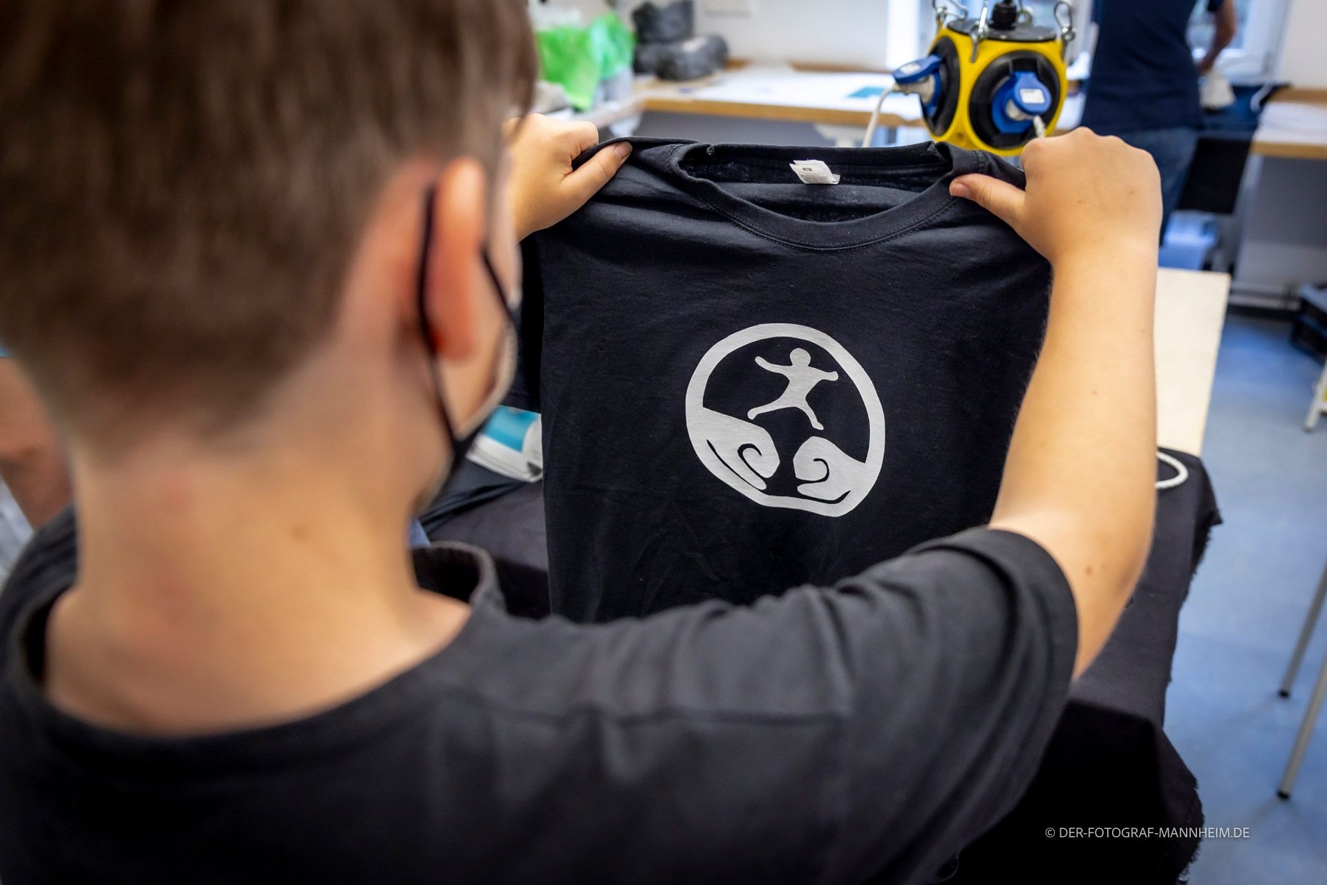 Ein Junge begutachtet ein bedrucktes T-Shirt