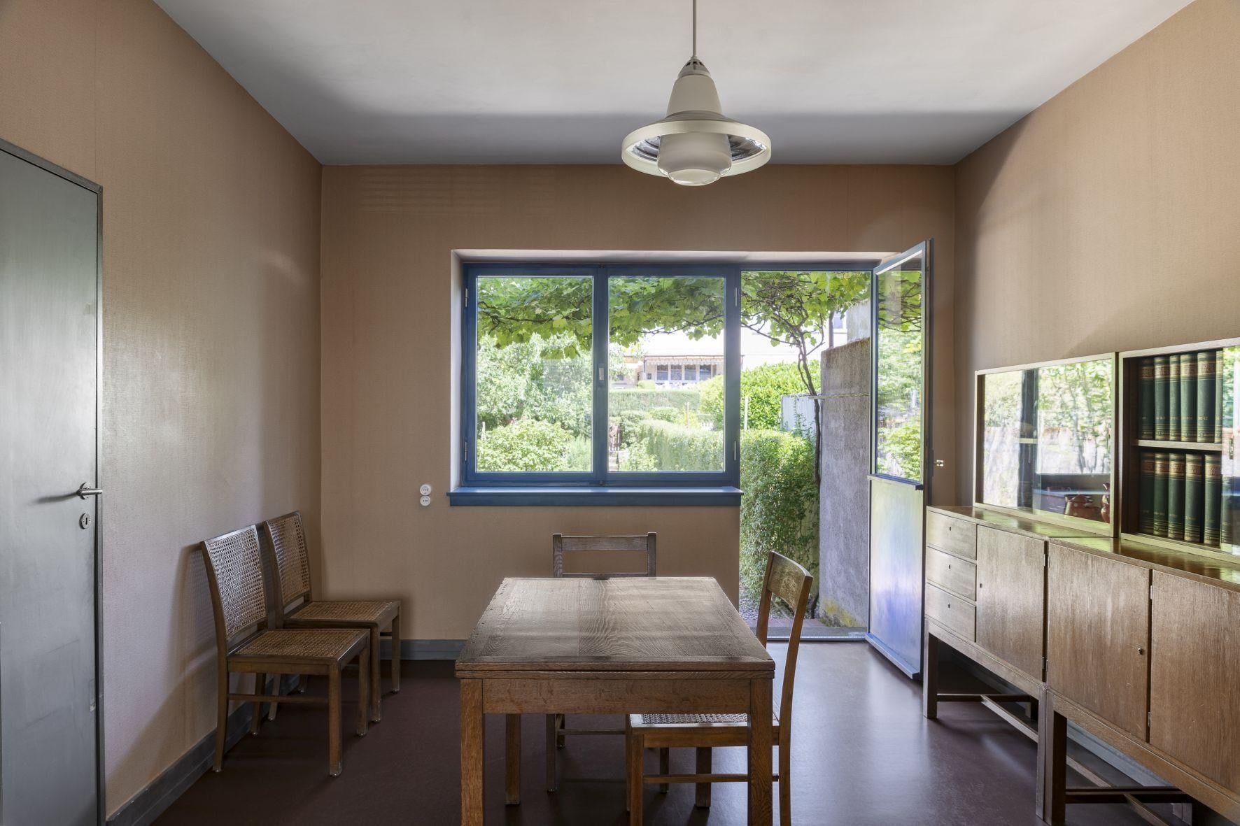 Bild einer Küche im Mayhus mit blauen Fensterrahmen und einem Tisch mit 4 Stühlen.