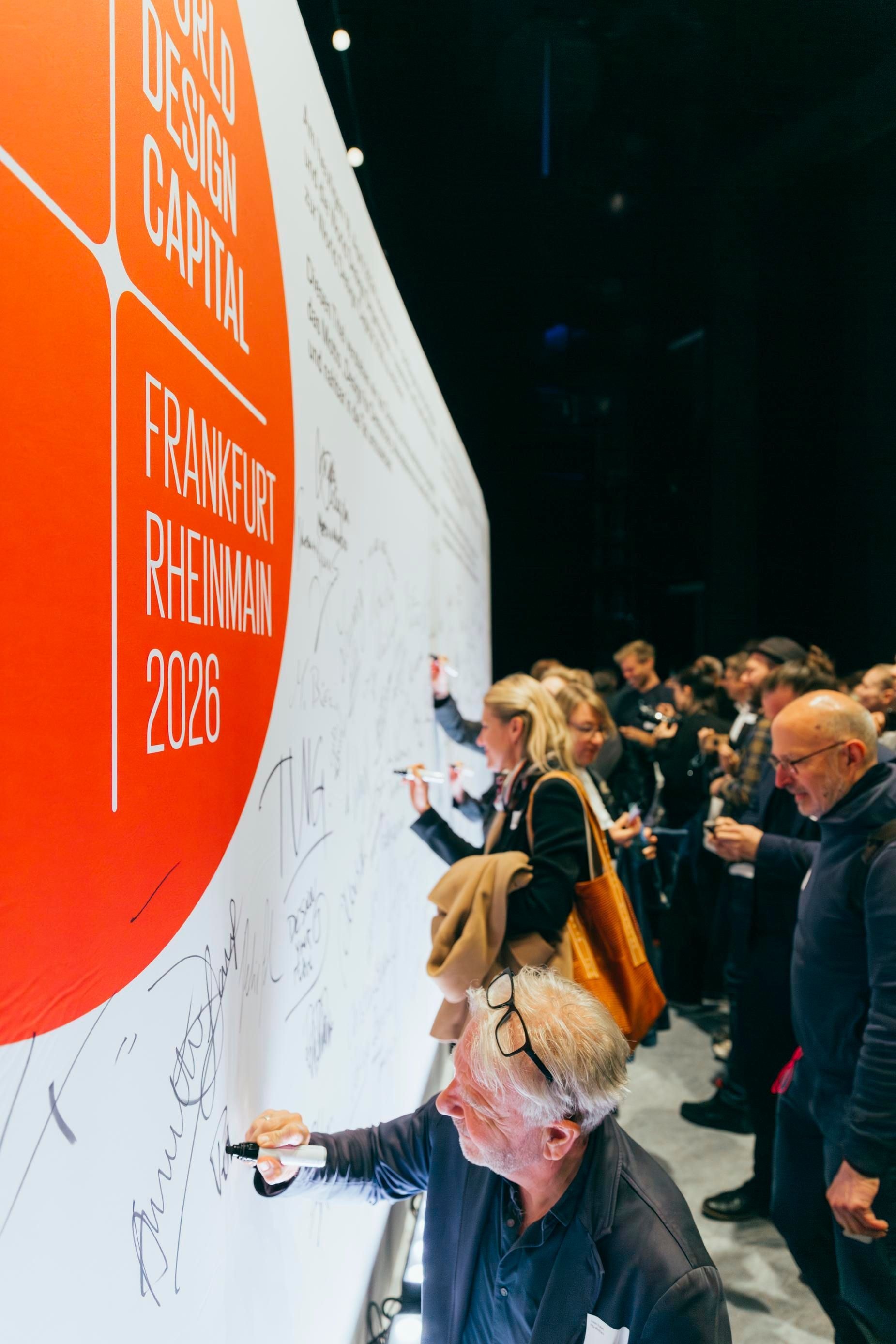 Viele Personen unterschreiben auf einer großen Tafel auf der Signing Ceremony von WDC 2026.