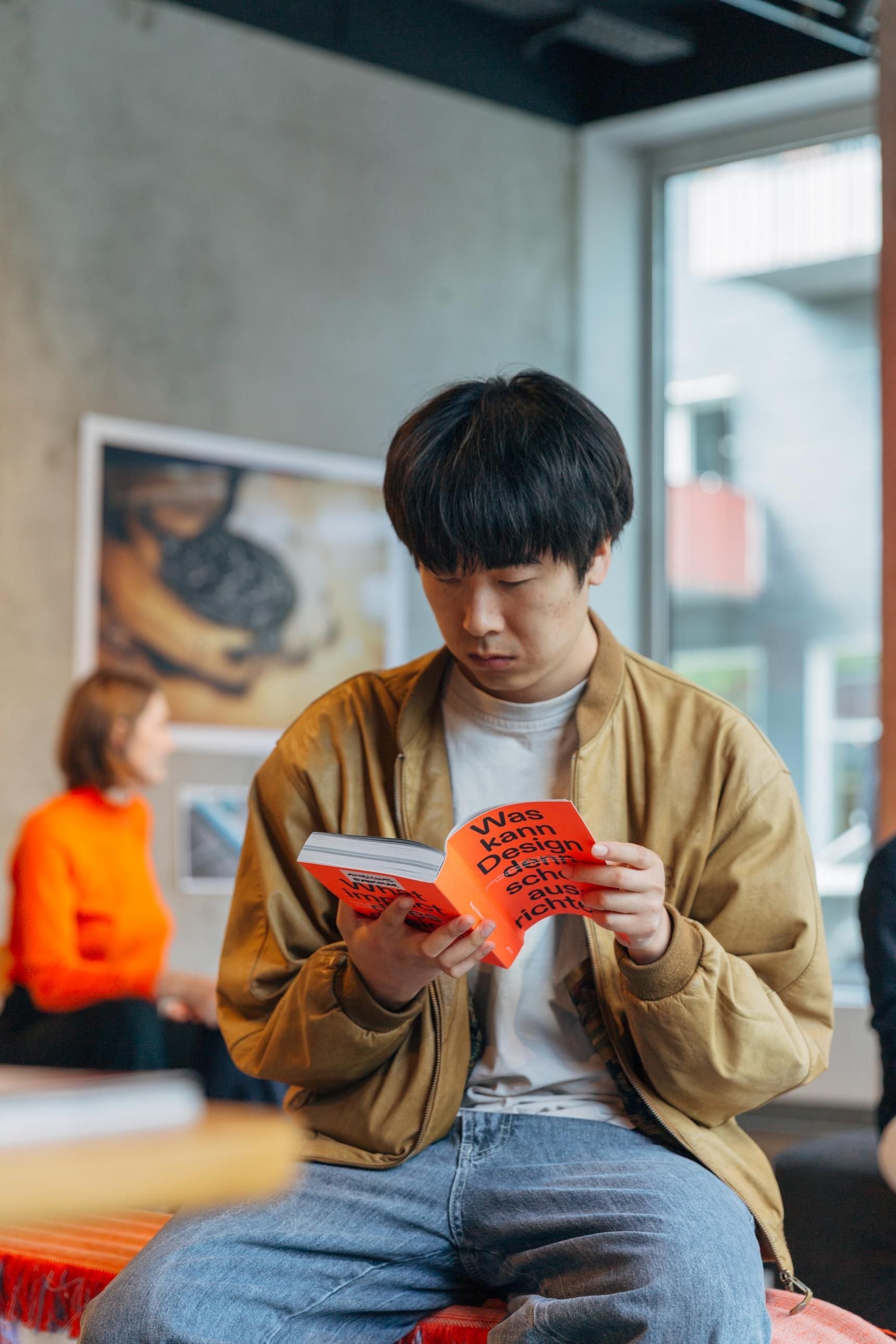 Eine Person hat den Design for Democracy Reader in der Hand und liest. 