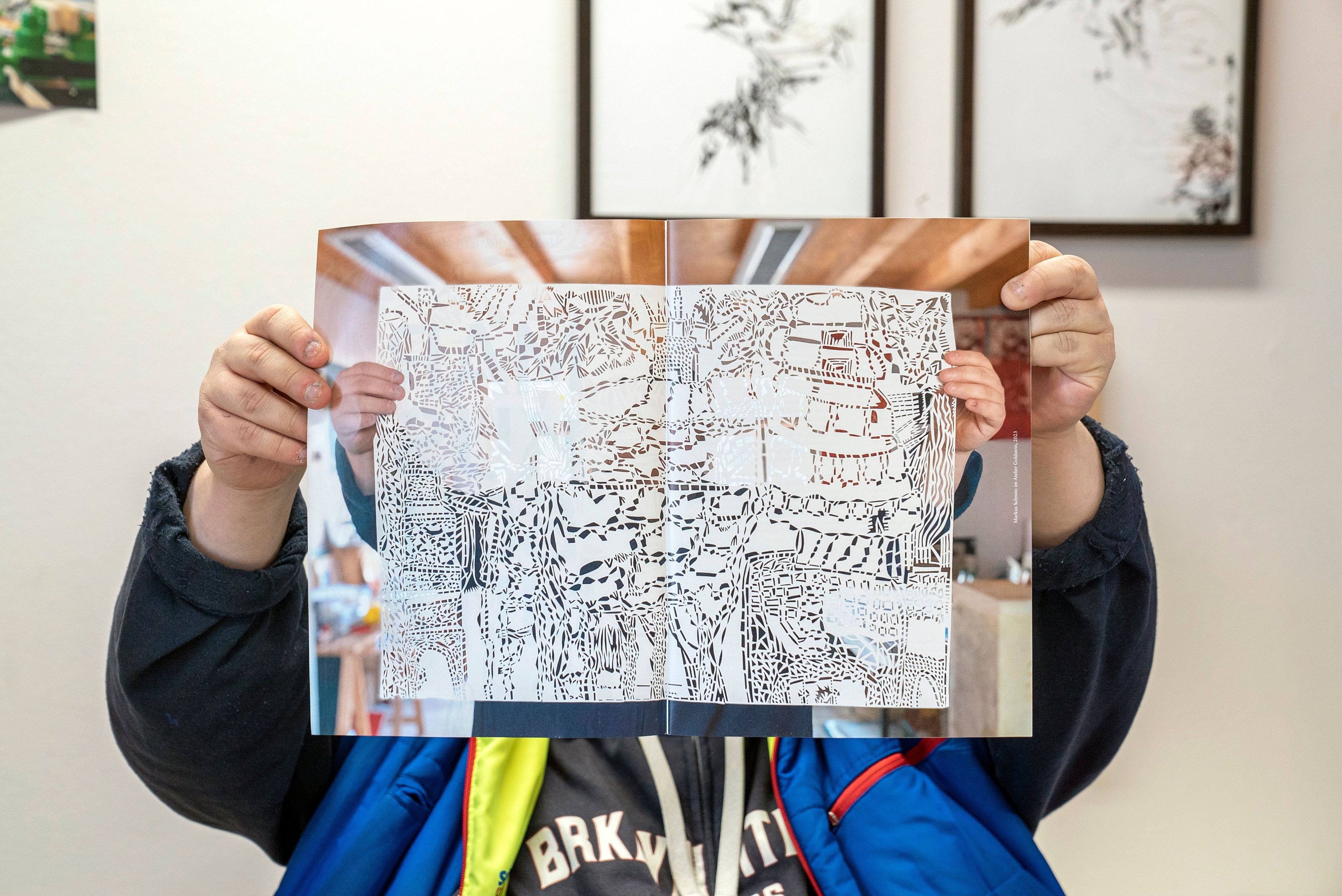 Ein Künstler hält ein ausgeschnittenes Papier vor sich. 