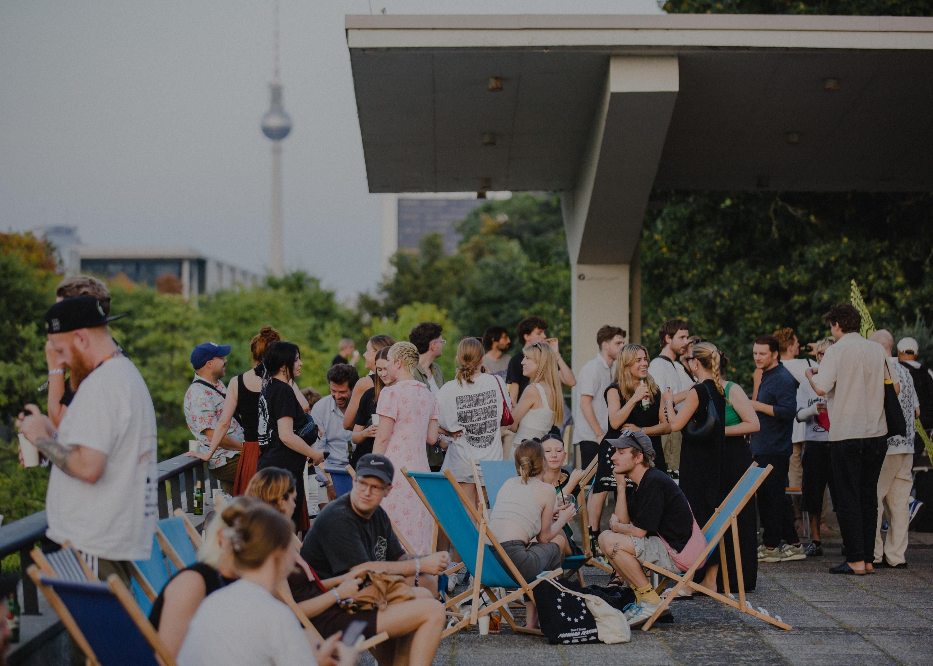 Menschen sitzen und stehen beim Forward Festival in Berlin.