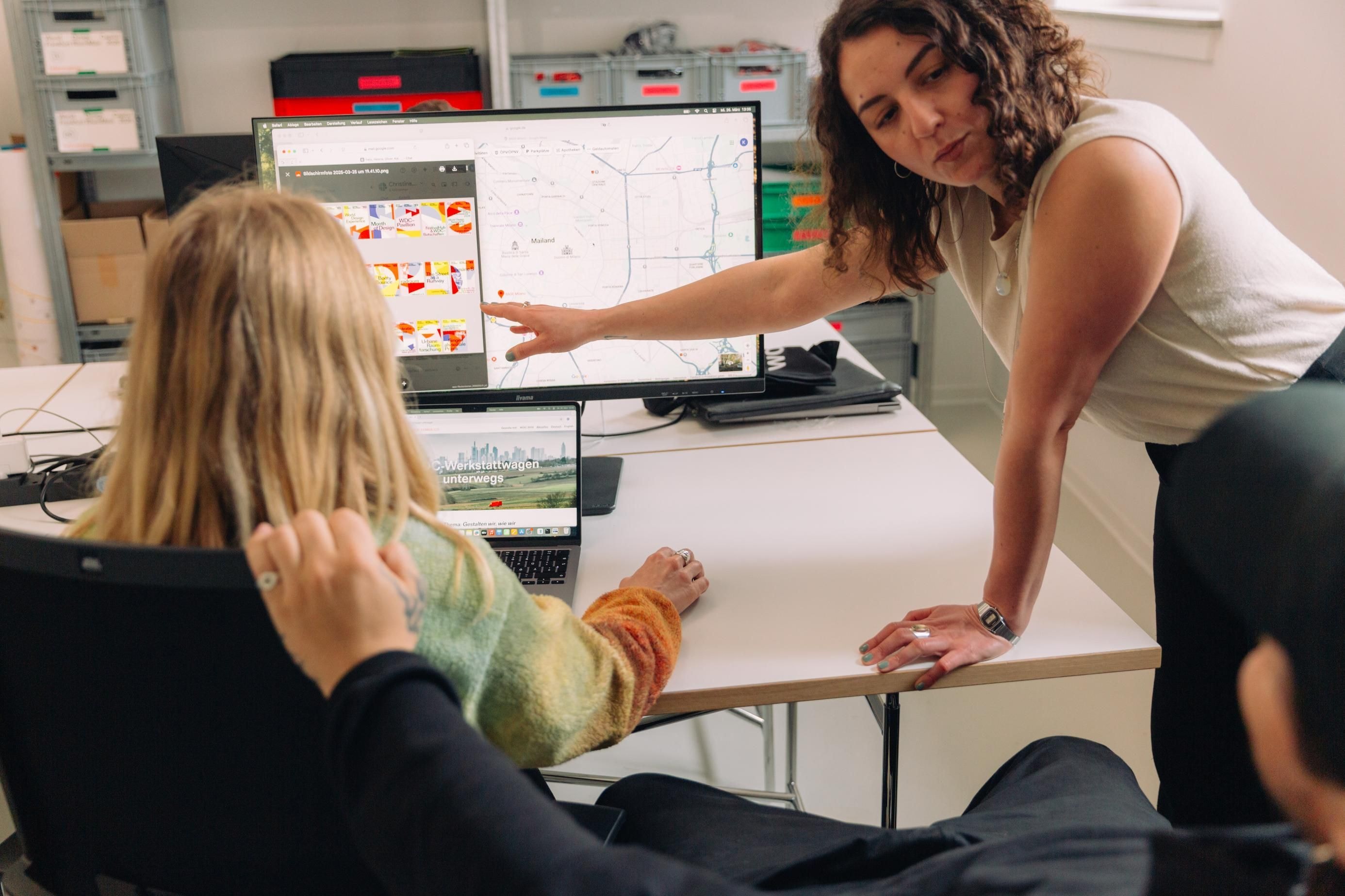 Drei Personen sitzen um einen Laptop herum und diskutieren.