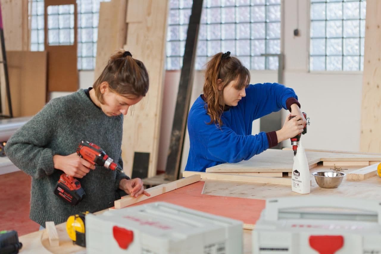 Zwei Frauen arbeiten mit Holz in einem Workshop.