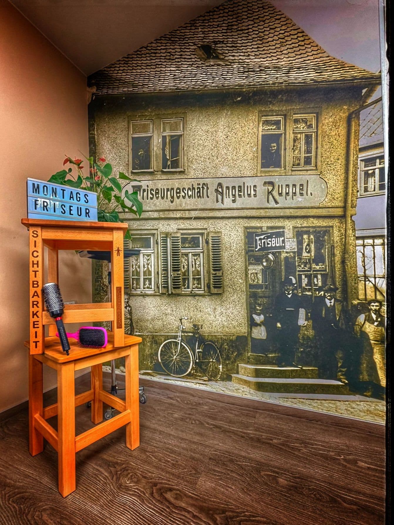 Inszeniertes Bild von Hockern und Bürsten vorn einer historischer Aufnahme