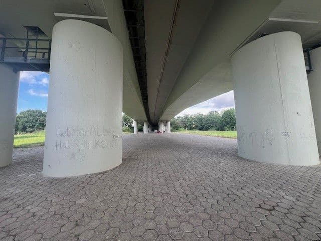 Zwei breite Säulen stützen eine Brücke, die sich bis ins Zentrum des Fotos erstreckt.