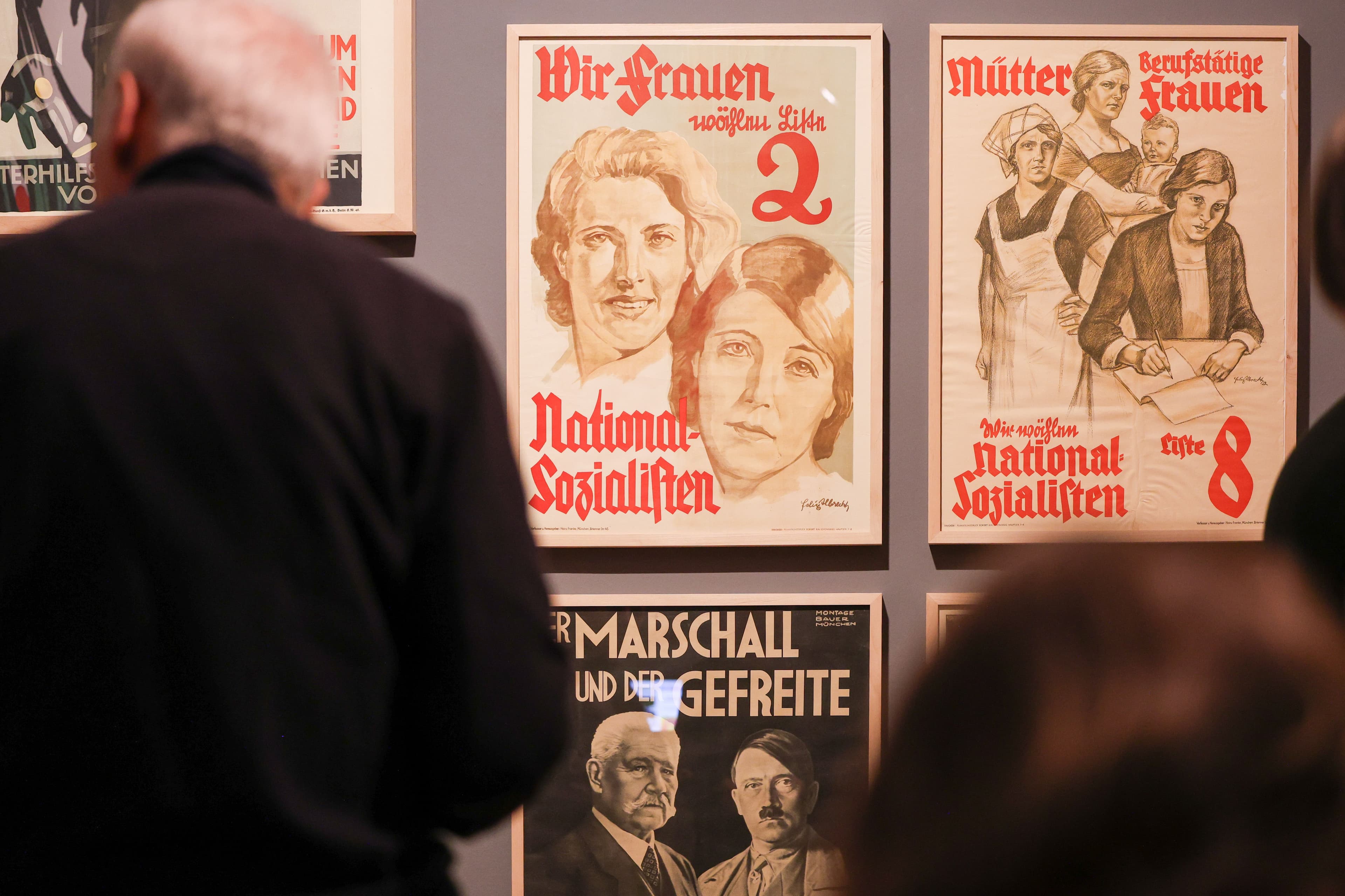 Plakate aus der Zeit des Nationalsozialismus werden in einer Ausstellung betrachtet