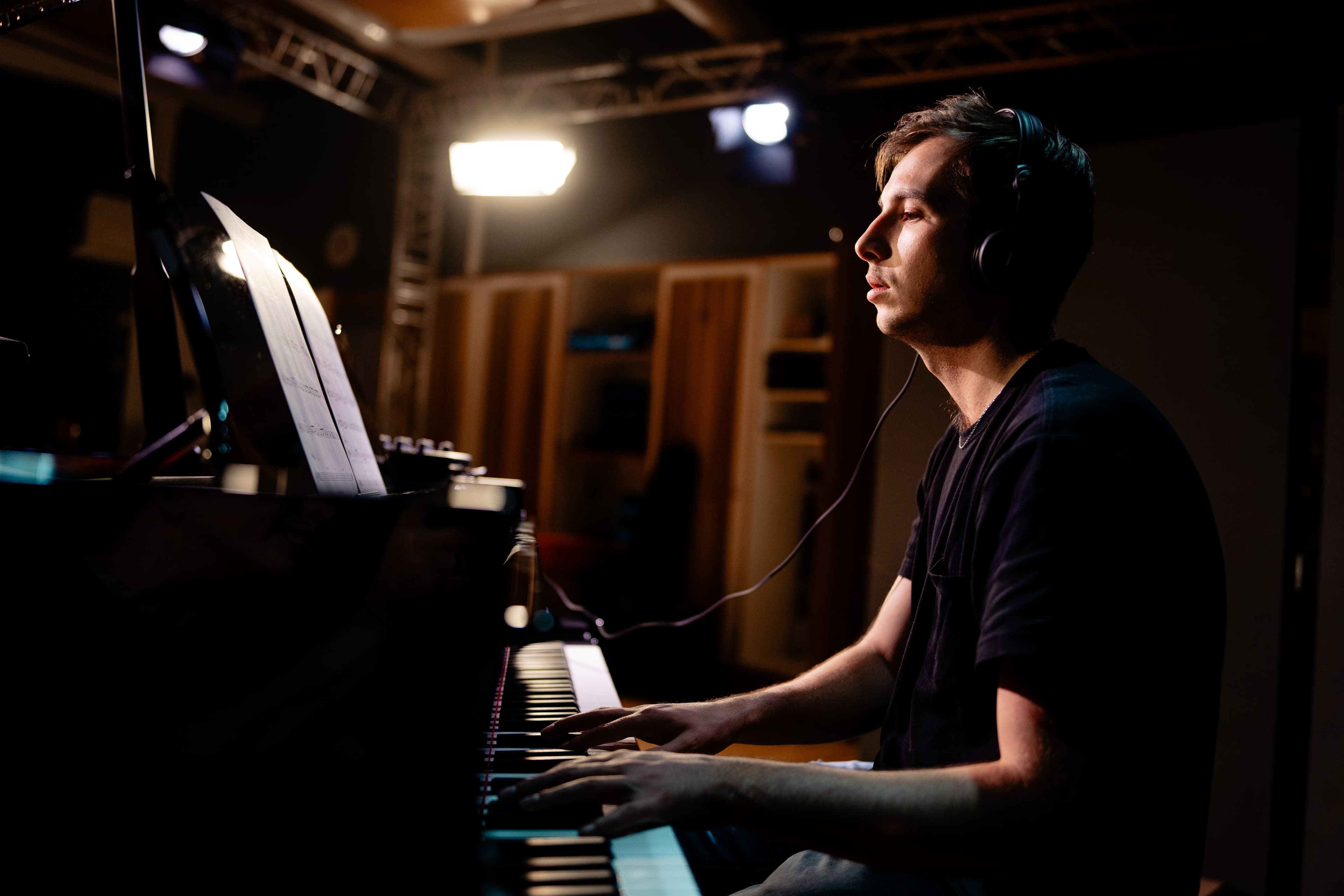 Ein Musiker sitzt mit Kopfhörern an einem Klaivier und musiziert.